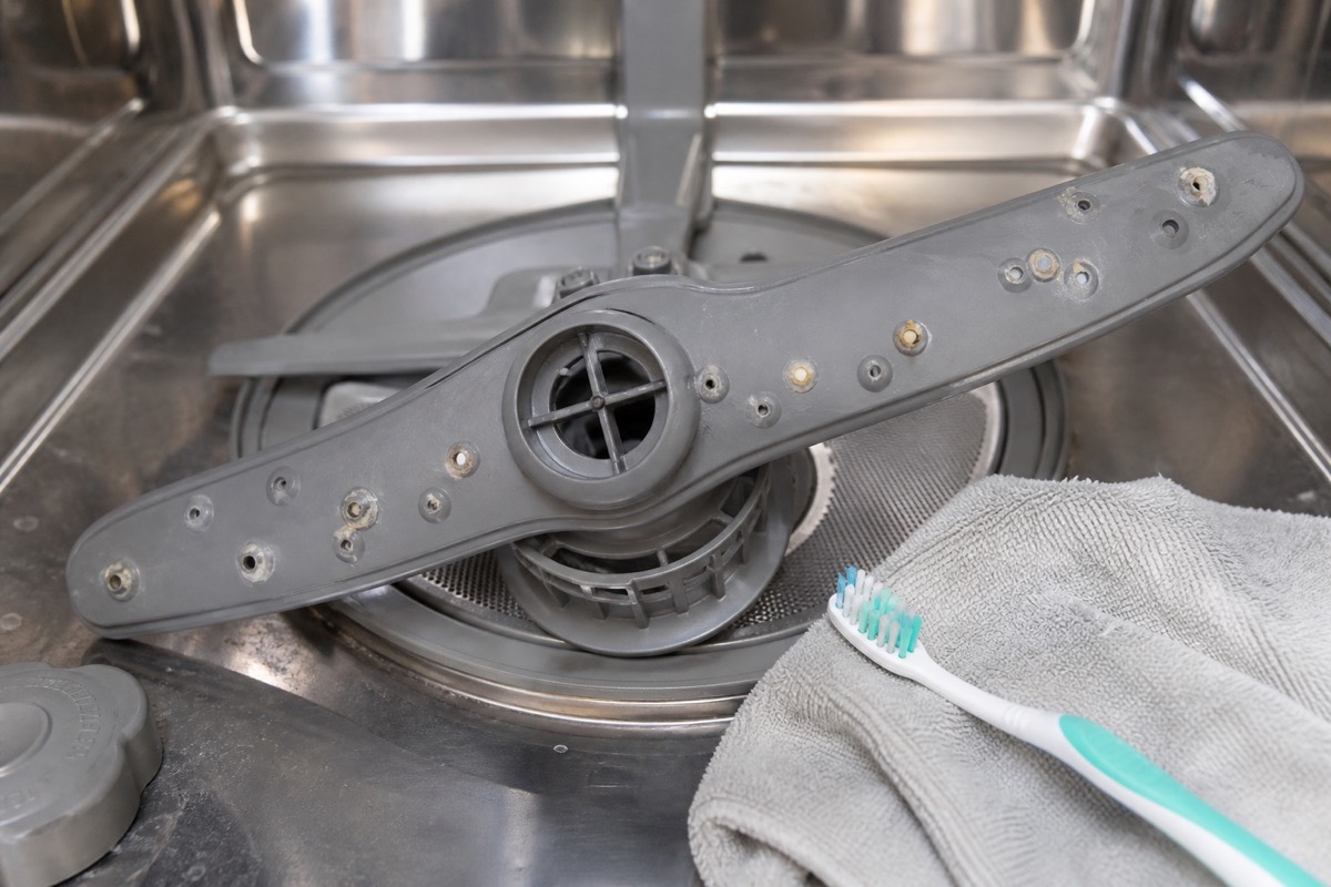 Dishwasher spray arm with mineral buildup around several blocked spray holes
