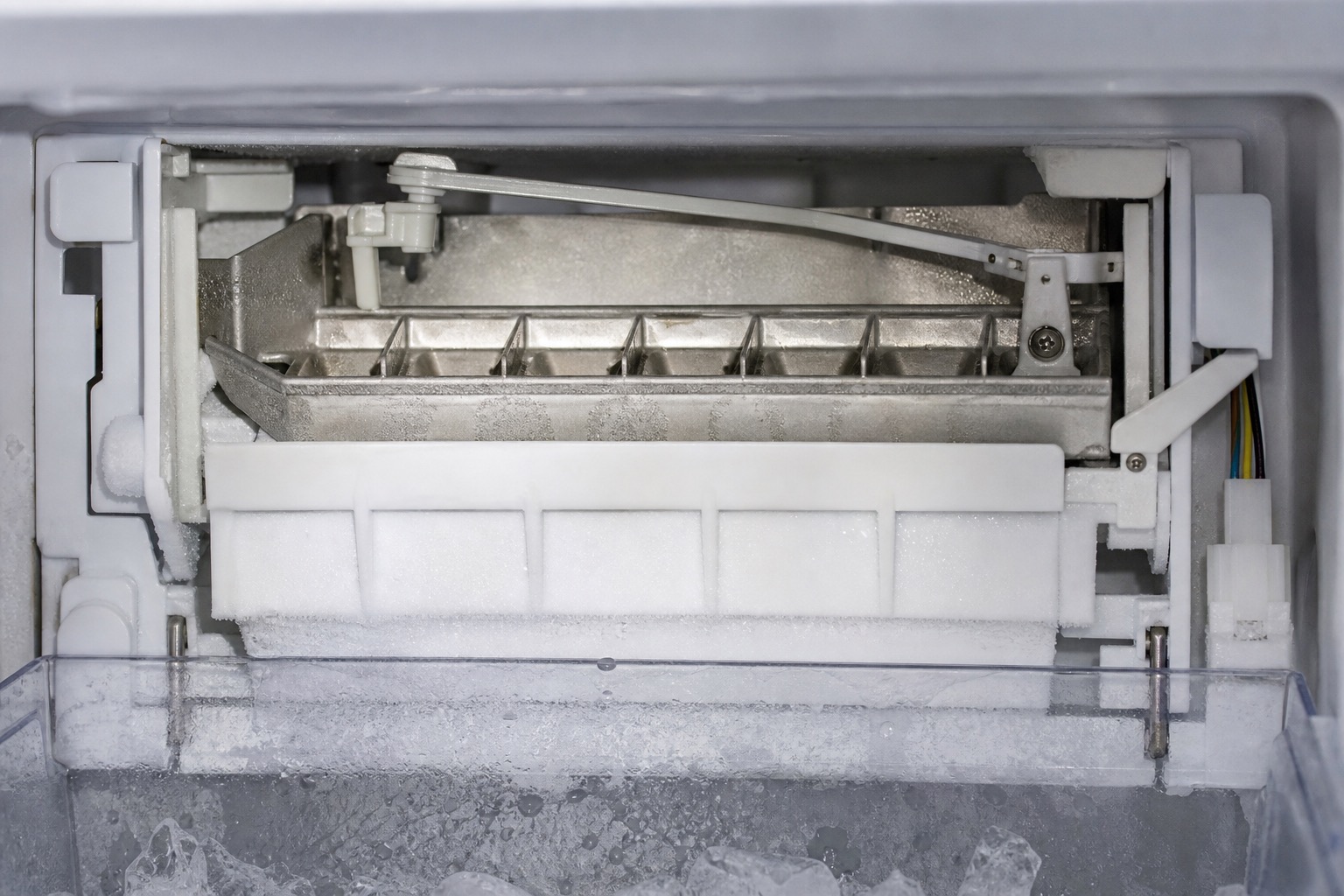 Ice maker tray and ejector arm inside a freezer compartment