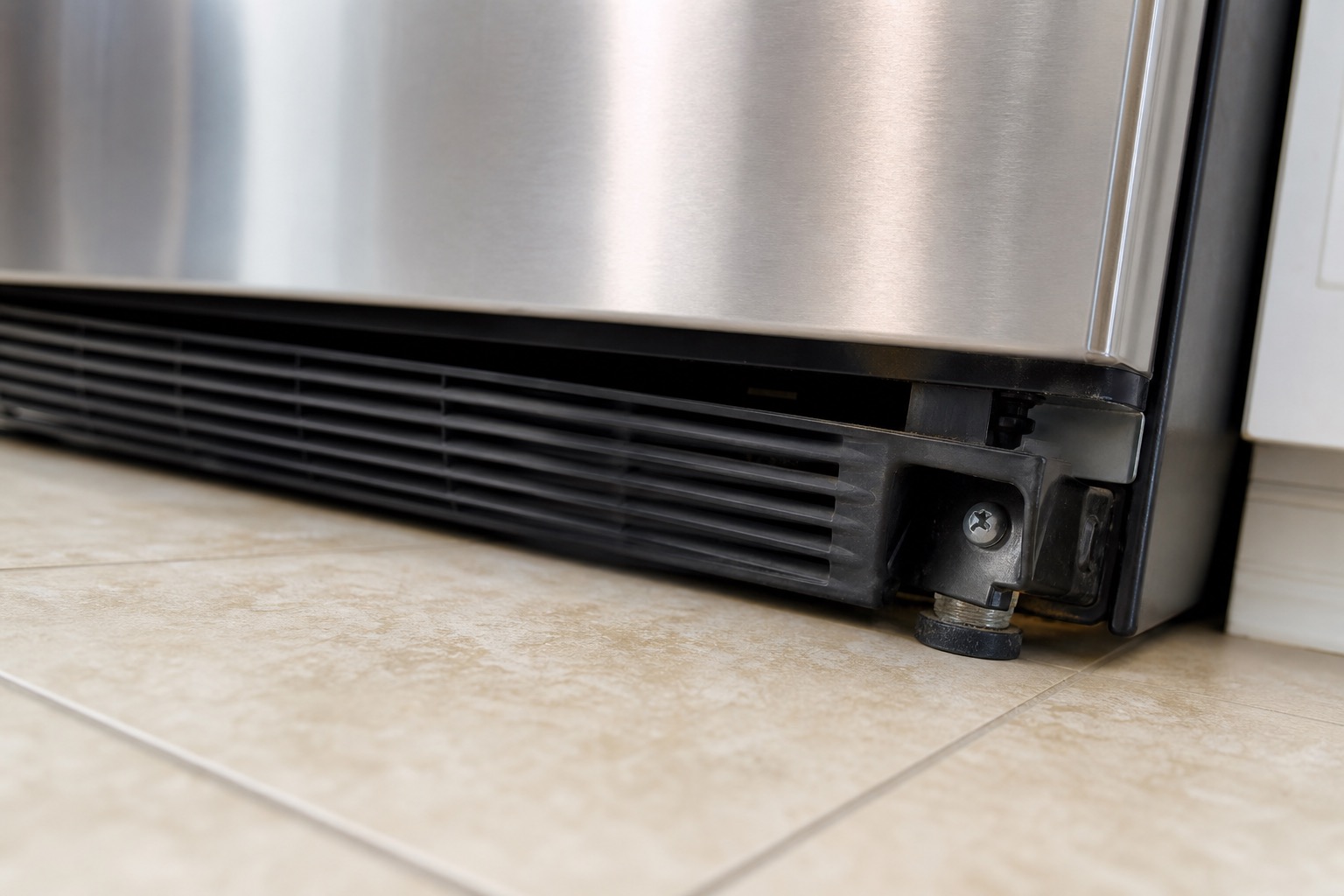 Lower refrigerator base grille and leveling foot related to buzzing vibration