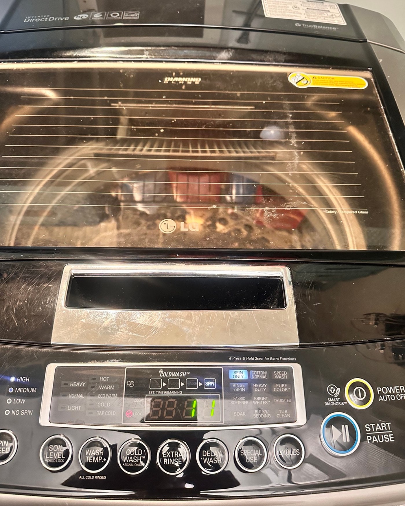 LG top-load washer with its control panel and glass lid visible.