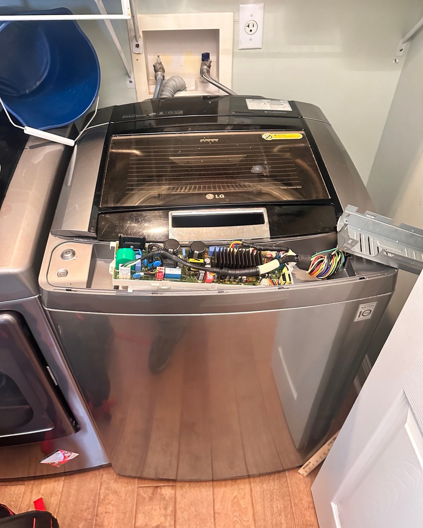 LG washer with the control panel opened and electronics visible.