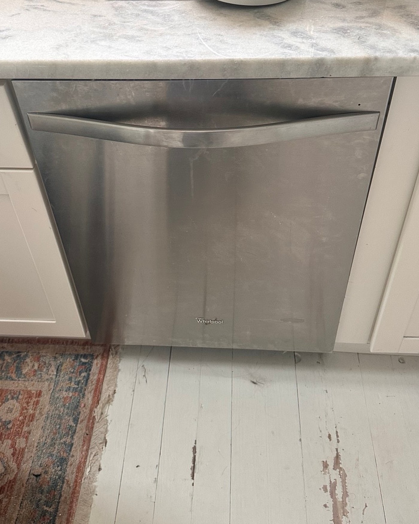 Stainless steel dishwasher installed beneath a kitchen counter.