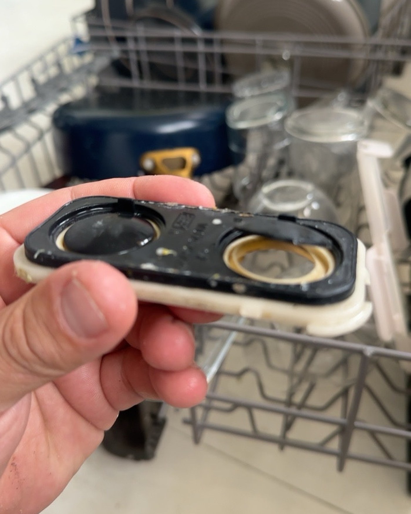 Dishwasher component held in front of the open dishwasher; screenshot controls cropped out.