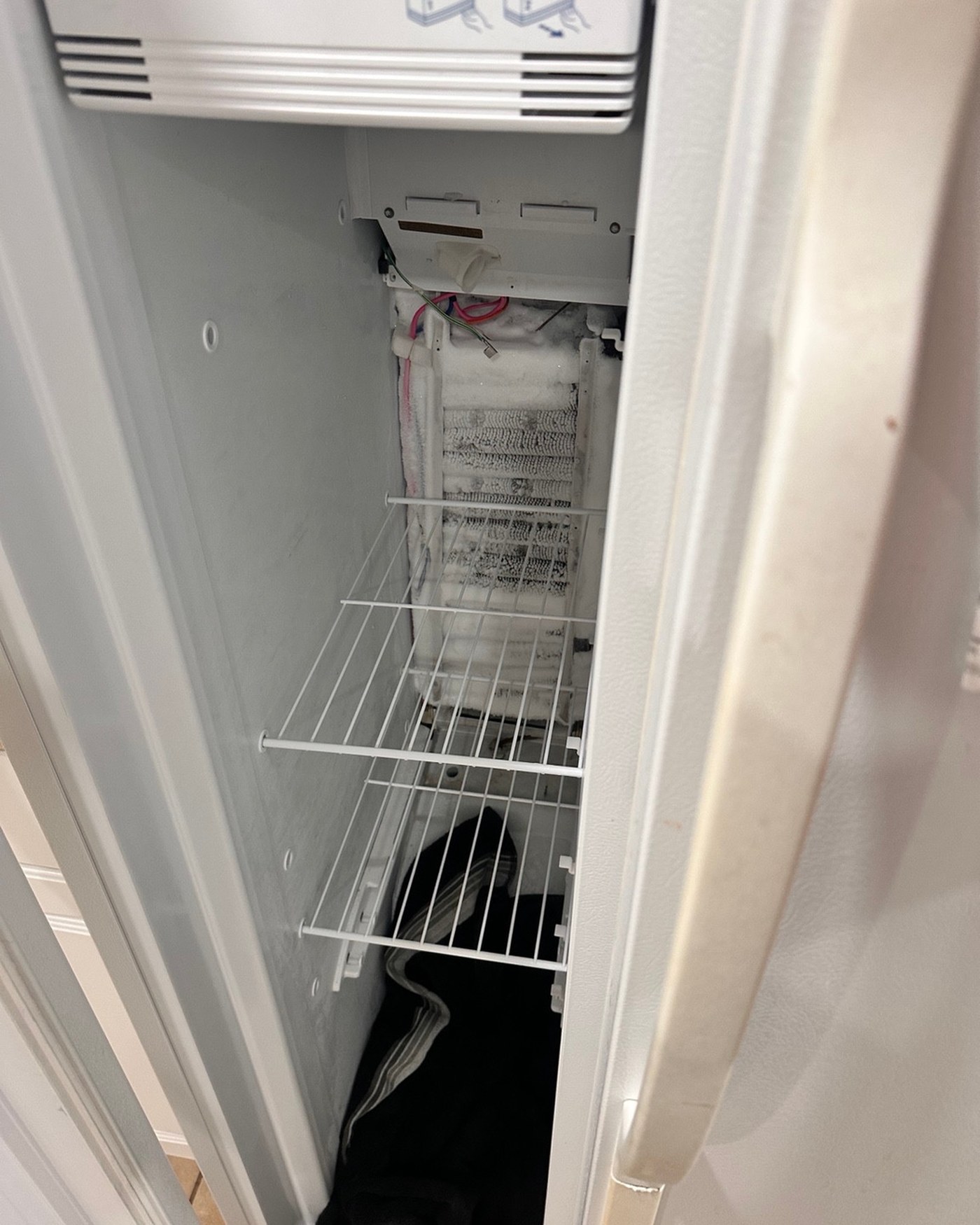 Frost and ice visible on the exposed refrigerator evaporator.