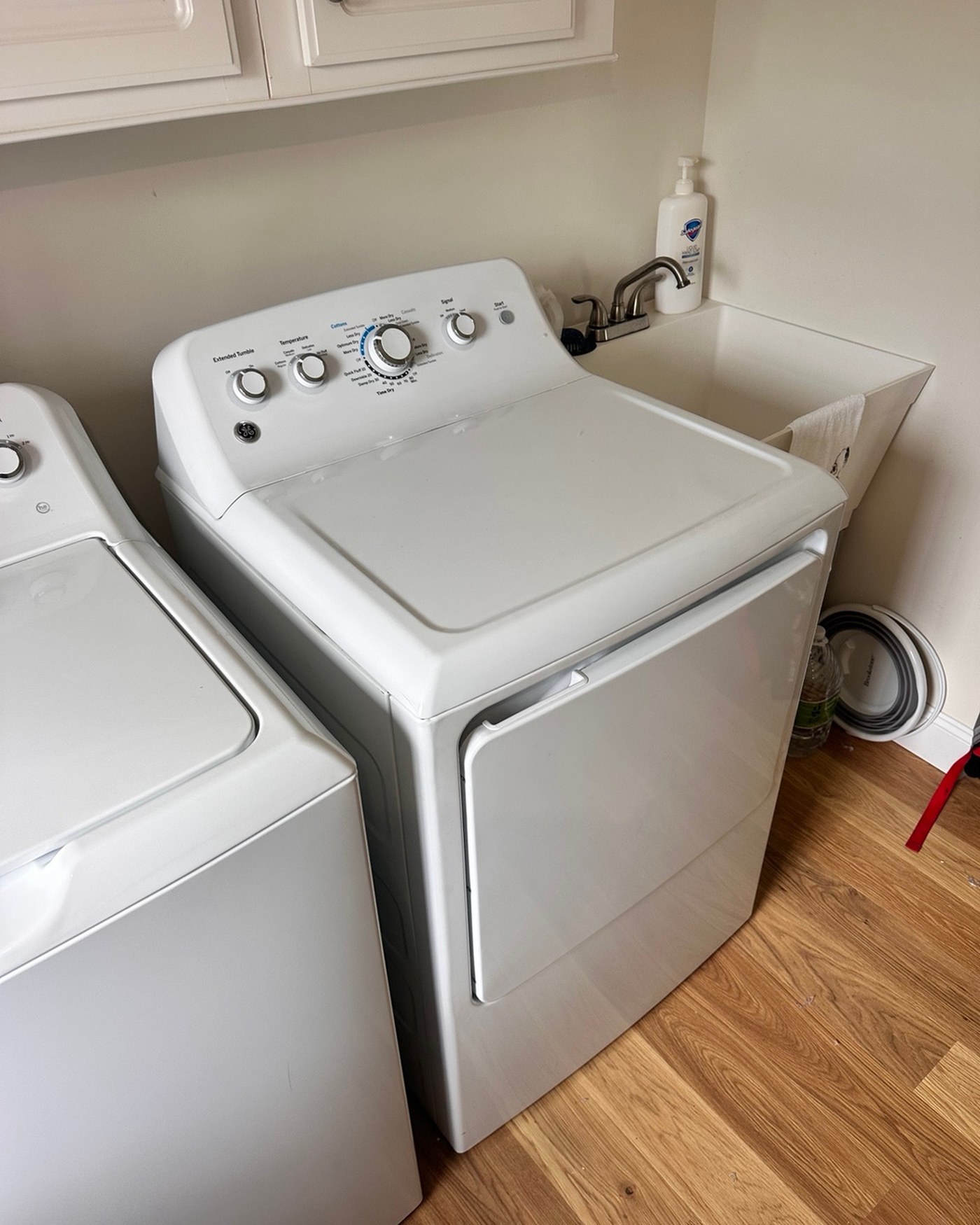White dryer beside a laundry sink.