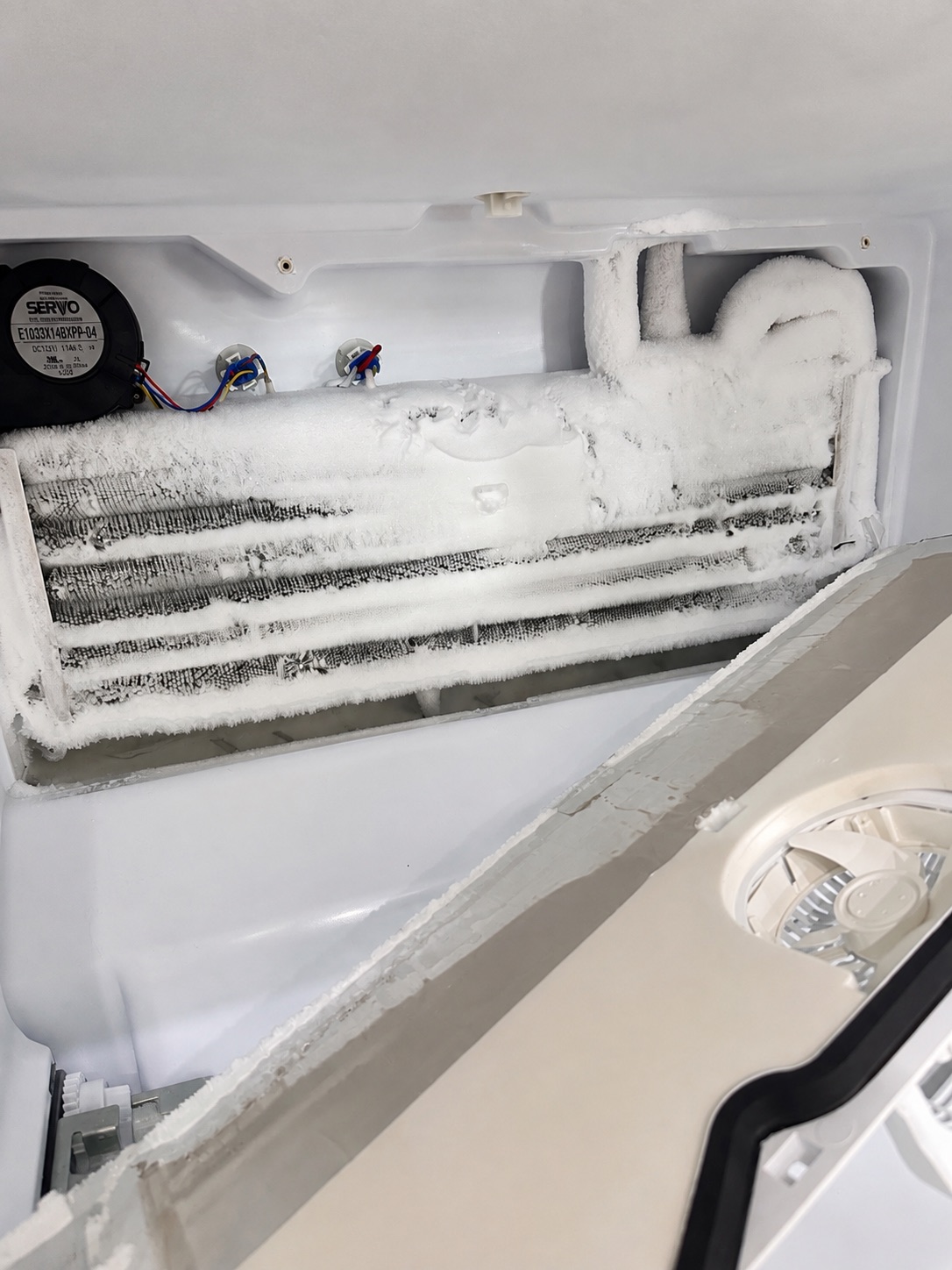 Heavily frosted evaporator on a GE GFE26GGKFBB refrigerator during a Fort Myers freezer cooling repair